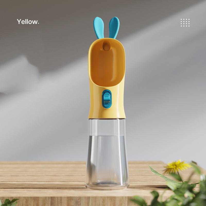 Yellow portable pet travel water bottle with silicone mouthpiece on wooden surface.