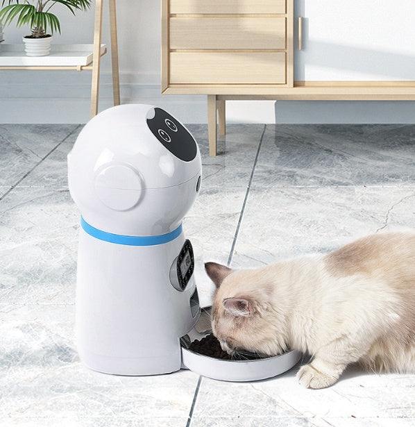 Automatic pet feeder dispensing food to a cat, featuring a removable grain storage barrel and metal food tray.